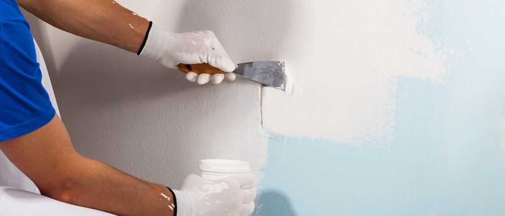 profissional passando massa acrílica numa parede azul | Como aplicar massa acrilica Blog Copafer
