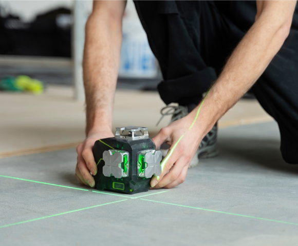 Profissional usando ferramenta à laser para tirar as medidas e nivelar piso corretamente